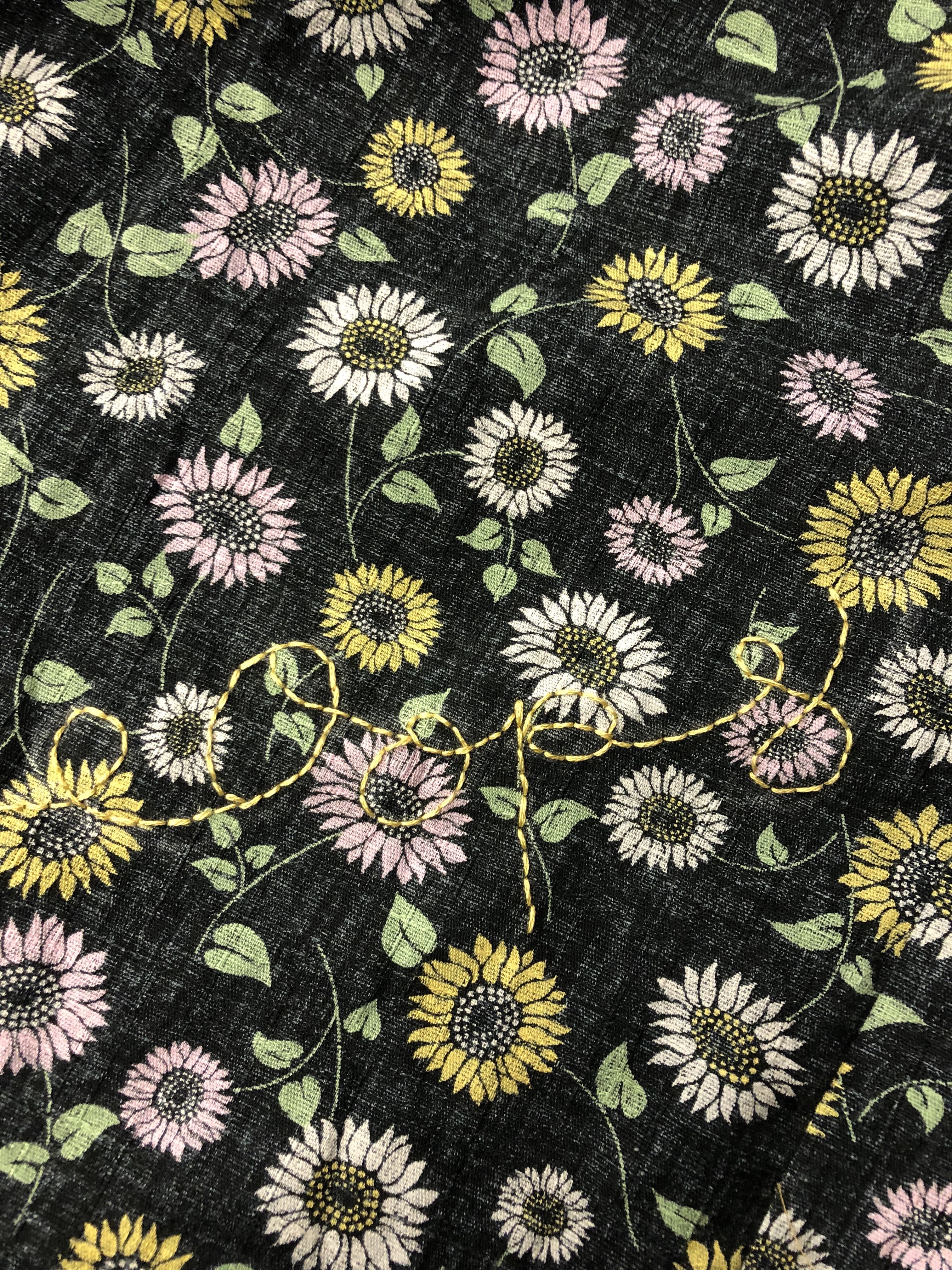 a gray floral print fabric with a the word oops embroidered on it in yellow